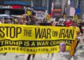 Demonstran membawa spanduk bertuliskan Stop the War on Iran Trump is a War Criminal di Amerika Serikat