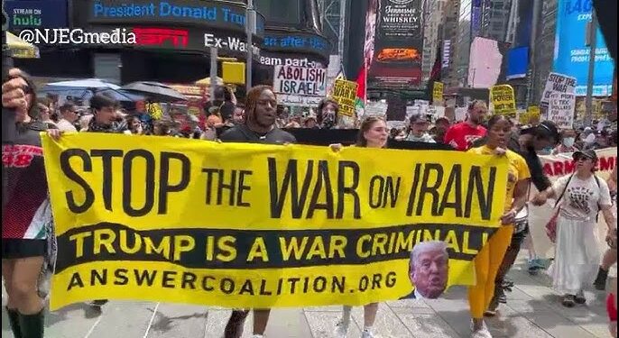 Demonstran membawa spanduk bertuliskan Stop the War on Iran Trump is a War Criminal di Amerika Serikat