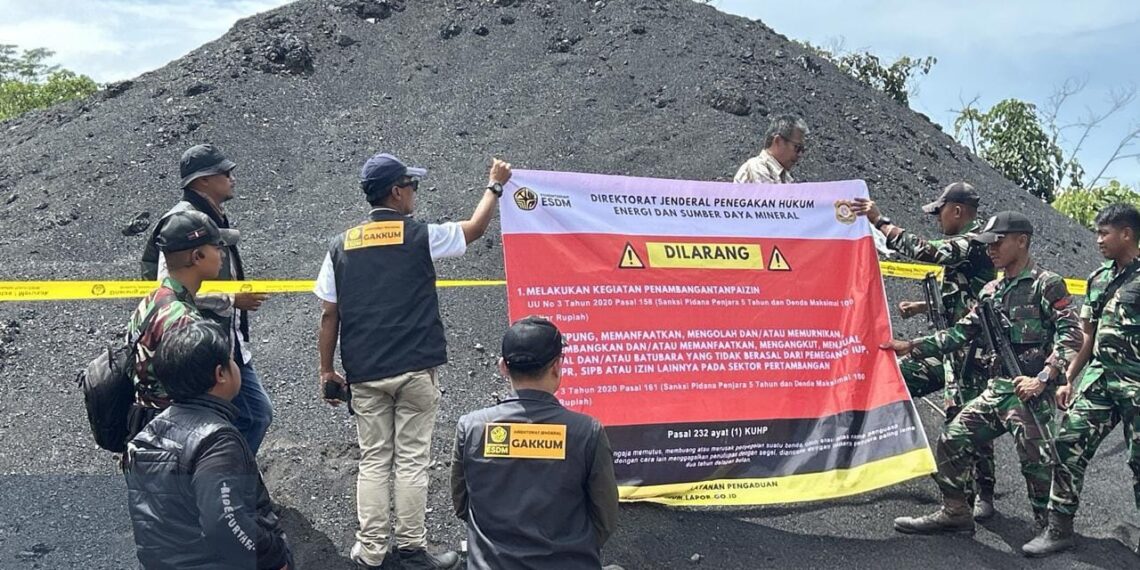 Petugas Ditjen Gakkum ESDM memasang segel dan garis pembatas pada tumpukan batubara ilegal hasil pertambangan tanpa izin di Kabupaten Kutai Kartanegara, Kalimantan Timur, akhir Desember 2025.