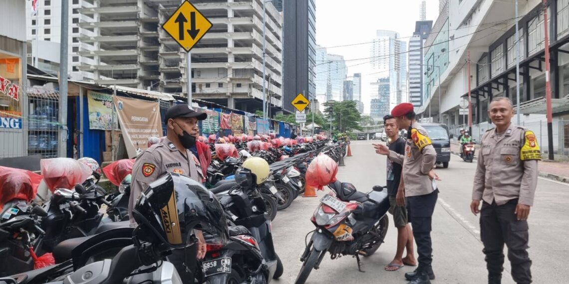 Personel Polsek Metro Setiabudi saat melakukan klarifikasi dan memberikan imbauan kepada juru parkir di kawasan Sudirman Tower, Jakarta Selatan. Penertiban dilakukan usai adanya laporan warga melalui layanan 110 terkait tarif parkir Rp10.000, Minggu (18/1/2026). (Foto: Dok. Humas Polri)