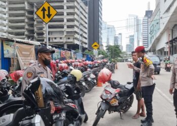Personel Polsek Metro Setiabudi saat melakukan klarifikasi dan memberikan imbauan kepada juru parkir di kawasan Sudirman Tower, Jakarta Selatan. Penertiban dilakukan usai adanya laporan warga melalui layanan 110 terkait tarif parkir Rp10.000, Minggu (18/1/2026). (Foto: Dok. Humas Polri)