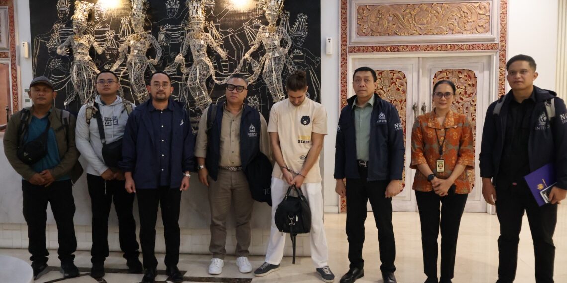 Personel Intelijen dan Penindakan Keimigrasian (Inteldakim) Ngurah Rai bersama anggota Polri saat melakukan pengawalan deportasi buronan Interpol berinisial CCZ di Bandara I Gusti Ngurah Rai, Bali, Selasa (20/1/2026).