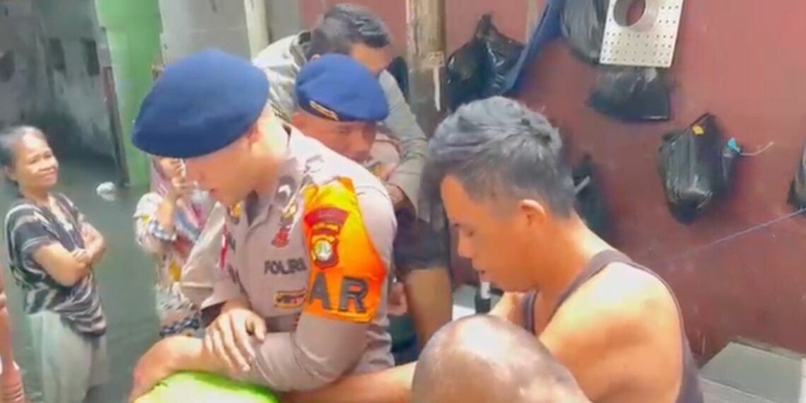Personel SAR Brimob Polda Metro Jaya saat mengevakuasi warga yang sedang sakit di tengah kepungan banjir Jakarta Barat, Kamis (29/1/2026). Selain evakuasi, Polri menyiagakan layanan darurat 110 untuk merespons kebutuhan masyarakat di lokasi bencana. (Foto: Dok. Humas Polda Metro Jaya/Ekoin.co)
