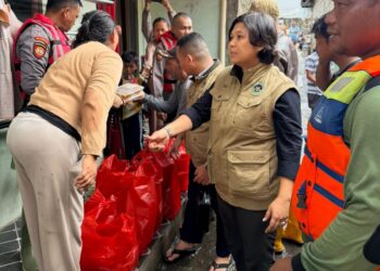 Personel Sat Samapta Polres Metro Bekasi Kota menyalurkan nasi siap saji kepada warga terdampak banjir di Kampung Lebak, Kelurahan Teluk Pucung, Bekasi Utara, Jumat (30/1/2026).