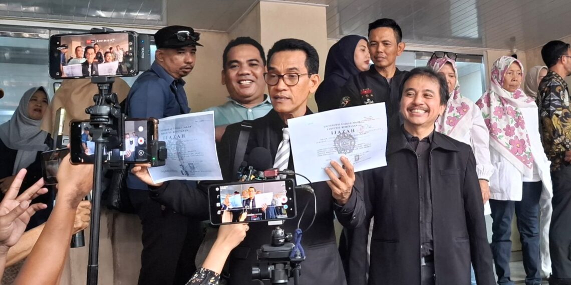 Tersangka kasus dugaan pencemaran nama baik, Roy Suryo, menunjukkan dua lembar salinan ijazah terlegalisasi milik Presiden ke-7 RI Joko Widodo di Mapolda Metro Jaya, Jakarta, Kamis (12/2/2026).