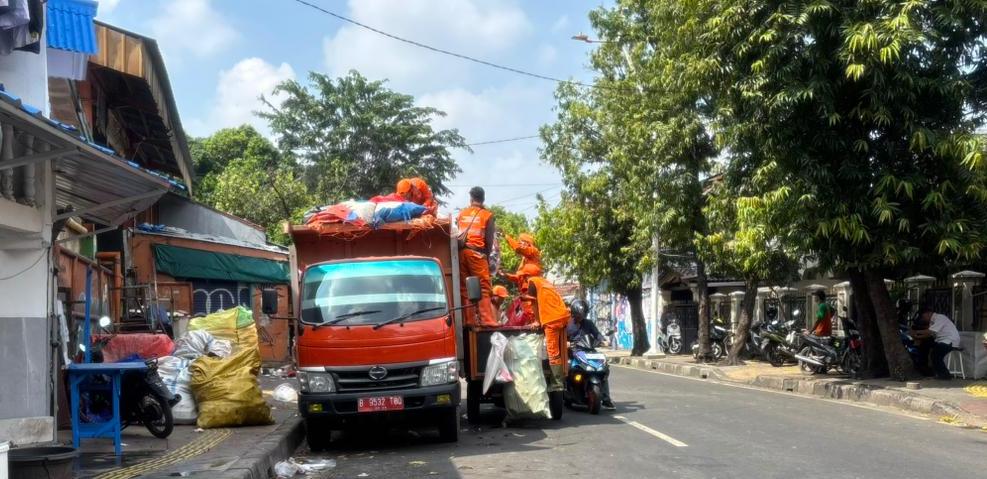 Petugas kebersihan mengangkut tumpukan sampah menggunakan truk di kawasan permukiman Jakarta, menyusul berkurangnya pengiriman ke TPST Bantar Gebang akibat longsor.