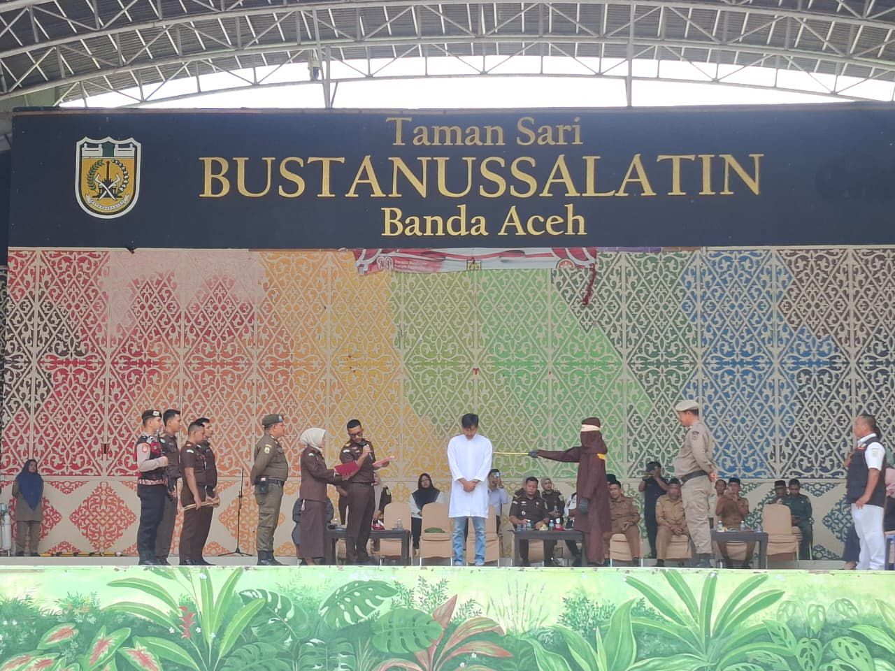 Salah seorang terpidana saat menjalani eksekusi uqubat cambuk di atas panggung Taman Bustanussalatin, Banda Aceh, Selasa (7/4/2026). Kejari Banda Aceh mengeksekusi enam pelanggar Hukum Jinayat dengan rincian dua terpidana zina dihukum 100 kali cambuk, sementara sisanya terbukti melakukan ikhtilat dan maisir. (Foto: Ist/Ekoin)