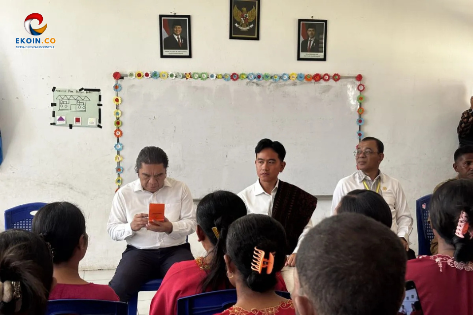 Panel discussion at a community event: four men seated at front, audience facing them, with a decorated whiteboard behind.