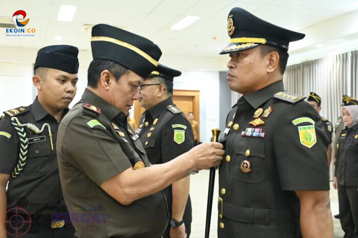 Senior officer pins a medal on a fellow officer during a formal military ceremony; other uniformed officers observe.