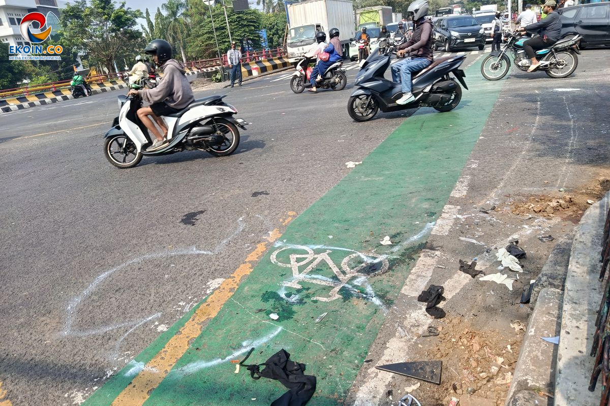 Busy urban street with several motorcyclists in traffic and a green-painted bike lane along the curb; litter and debris on the sidewalk nearby; logo watermark in the top-left corner.